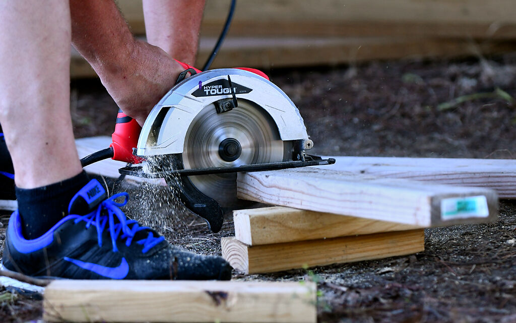 Doug Shinn uses a circular saw to saw strips of wood into blocks